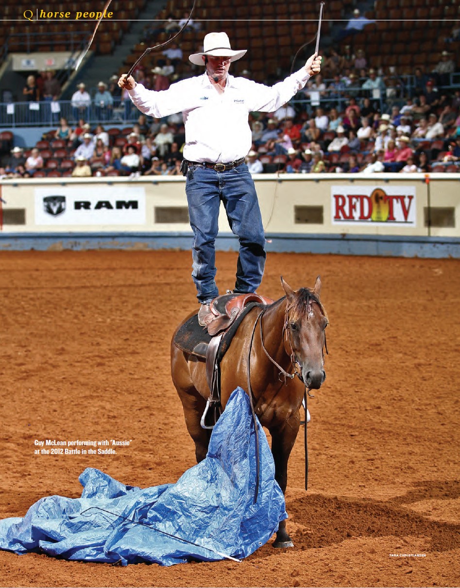 Trainer performing a liberty and trick riding demonstration on a Quarter Horse during a western horsemanship event. Showcasing trust, balance, and advanced horse training before a live arena audience.
